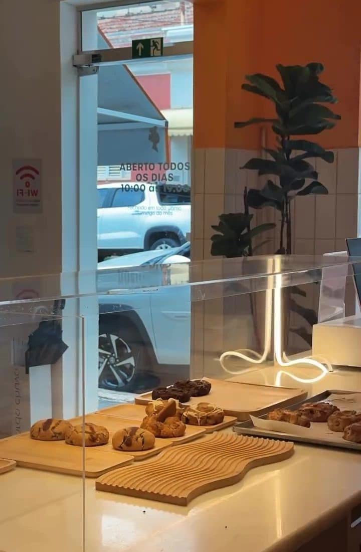 A vitrine de cookies junto da janela, com a parede laranja e a porta para a rua